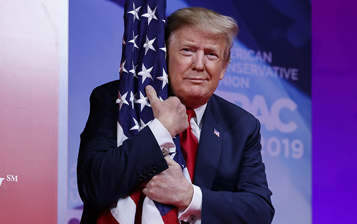 Il presidente Usa Donald Trump abbraccia la bandiera americana al suo arrivo al Conservative Political Action Conference, CPAC 2019, 2 marzo 2019